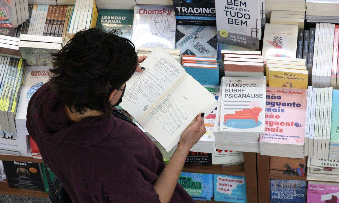 Mulher em pé lendo livro em biblioteca